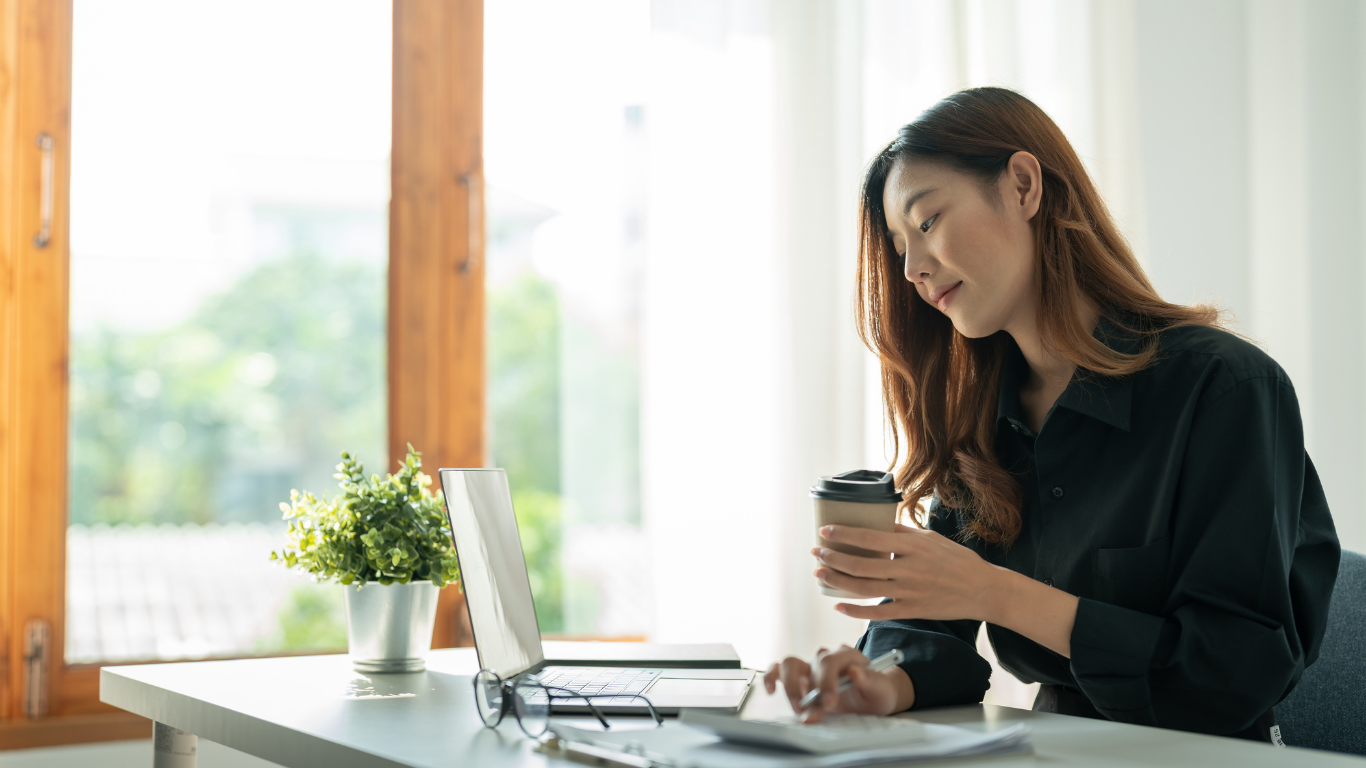 Morpheus Group | Remote Support That Feels In-House 1 Business owner smiling while working, holding a coffee cup at a desk