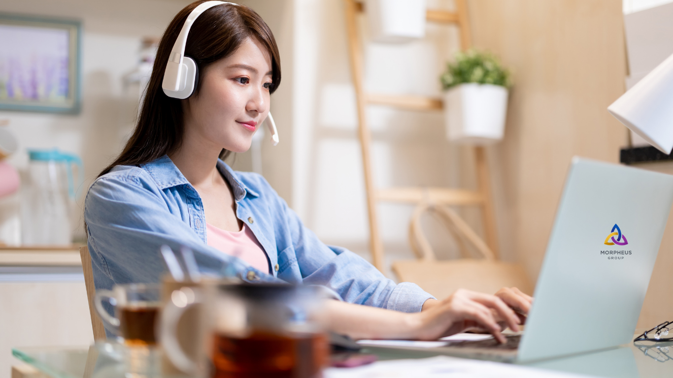 Morpheus Group | Remote Support That Feels In-House 2 Remote support professional wearing a headset, smiling while working from a bright home workspace